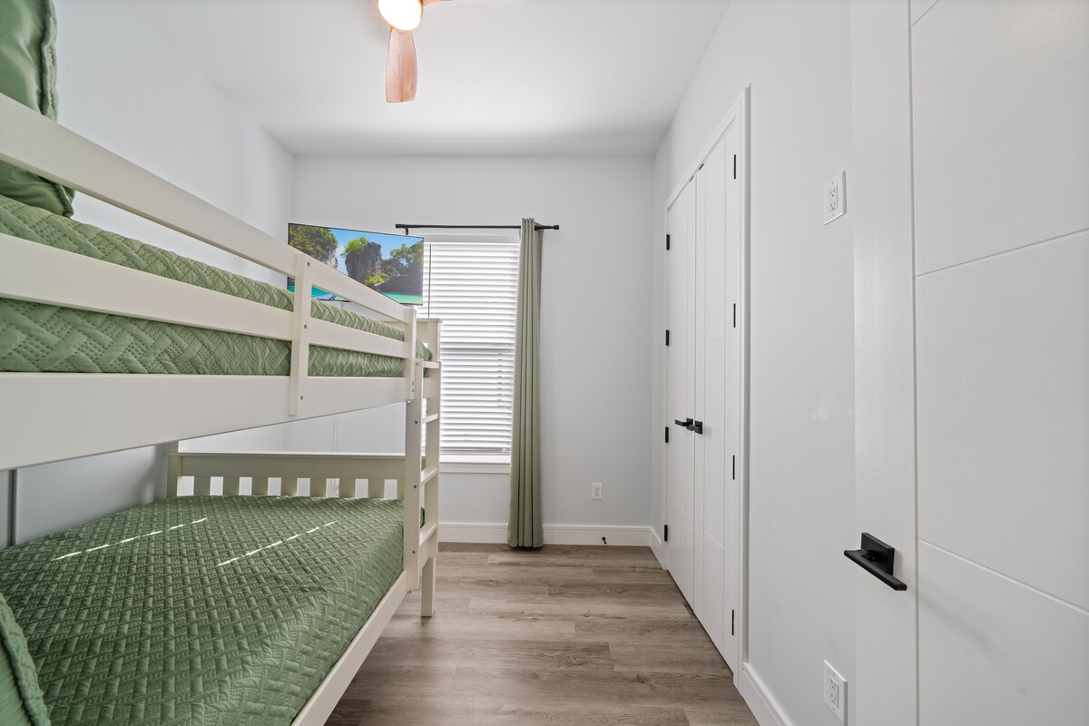 Spálňa s poschodovými posteľami a veľkým inteligentným televízorom