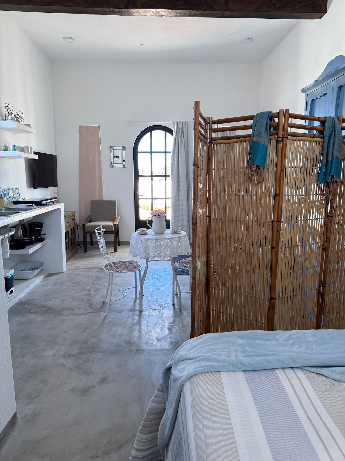 Genieße vom Bett aus das natürliche Licht und den Blick nach draußen durch die gewölbte Tür. Offenes Design kombiniert Komfort und Wärme zu einem funktionalen und einladenden Raum.