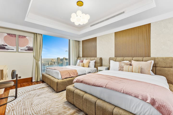 Habitación luminosa y moderna con dos camas, detalles en rosa suave y vistas a la ciudad.