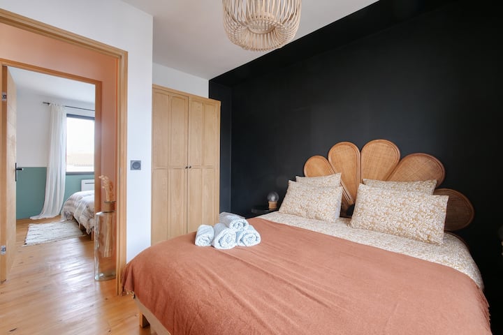 Habitación de estilo afirmado, con cabecero de ratán, pared negra profunda y toques naturales para un ambiente elegante y relajante.