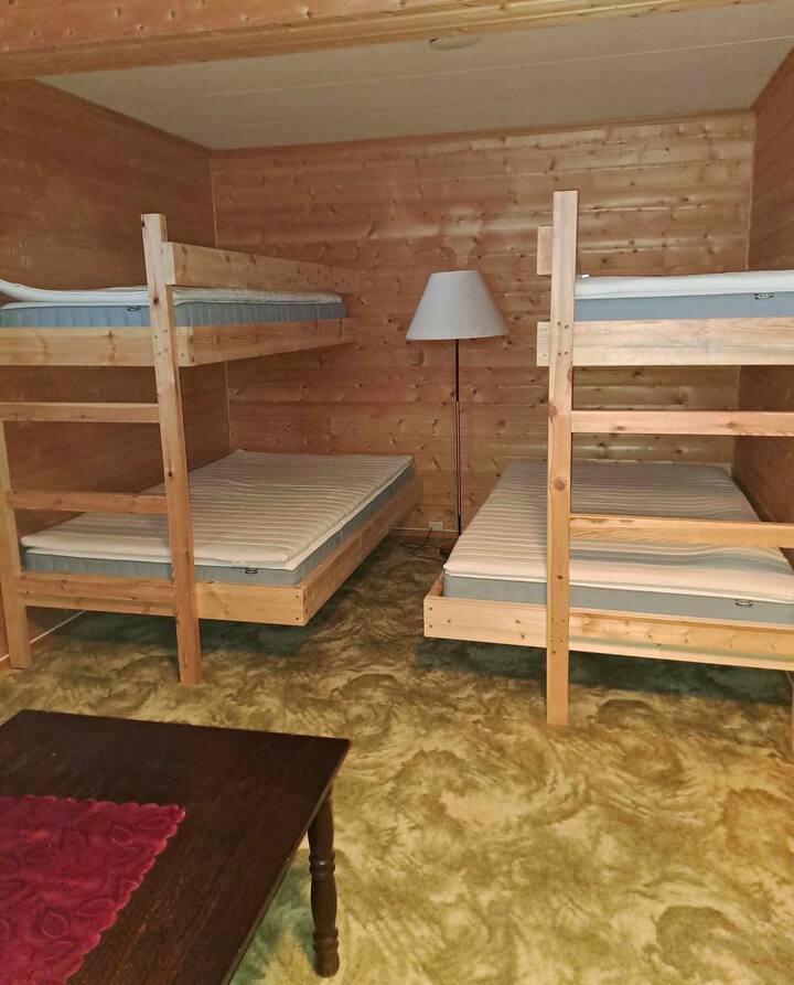 Plass til 4-6 personer på dette soverommet som ligger nede i en trapp. På rommet er det en vedfyrt komfyr og sofagruppe. 