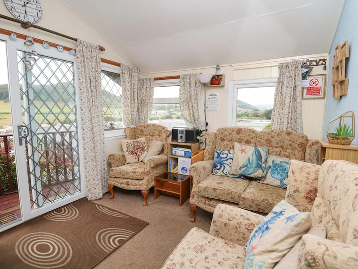 Après avoir monté quelques marches et obtenu la clé trhe, entrez par la porte patio dans le salon principal avec des chaises hautes à ailes traditionnelles et un canapé 2 places dans le salon. Vue sur le site à travers la porte patio et les fenêtres.