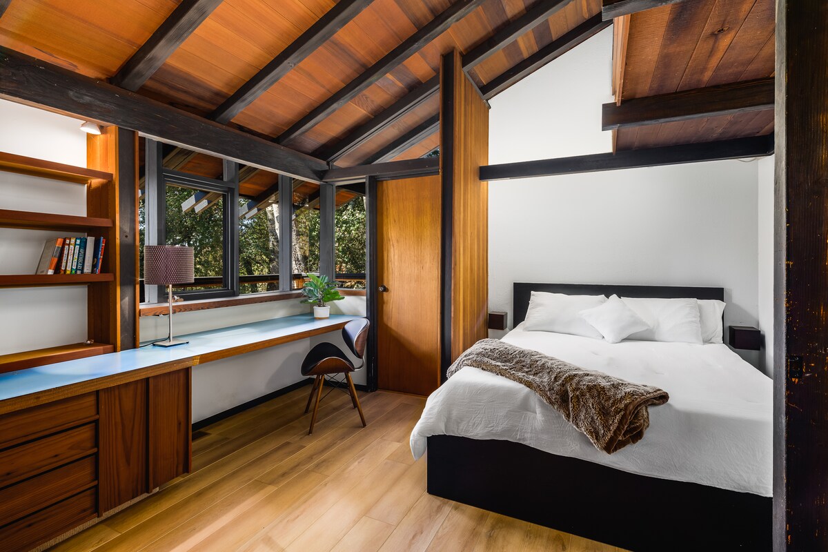 تتميز غرفة النوم الهادئة والأنيقة هذه بلمسات خشبية دافئة ومقعد نافذة مريح ونوافذ كبيرة تطل على مناظر الغابة الهادئة للاسترخاء التام.