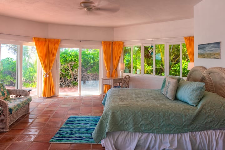 Dormitorio en la planta baja con cama tamaño king, sofá, escritorio, mininevera y zona de café, baño en suite y acceso directo a la piscina. Con aire acondicionado y ventilador de techo