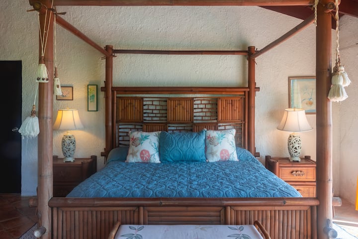 Dormitorio en la planta alta con cama tamaño king, aire acondicionado, ventilador de techo, baño privado y acceso directo a la terraza trasera con vistas al océano Atlántico.