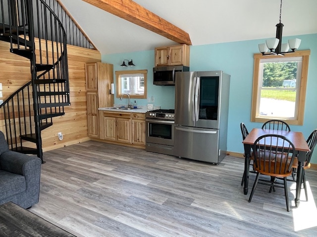 An open-concept living area features a modern kitchen with stainless steel appliances and wooden cabinetry. A dining table with six black chairs is positioned next to large windows, allowing natural light to fill the space. A spiral staircase leads to the upper level, adding architectural interest.