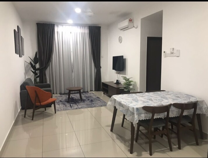 A bright living area features a gray sofa and an orange accent chair, positioned next to a round wooden coffee table. A dining table with wooden chairs is set nearby, and large windows are draped with gray curtains, allowing natural light to illuminate the space.
