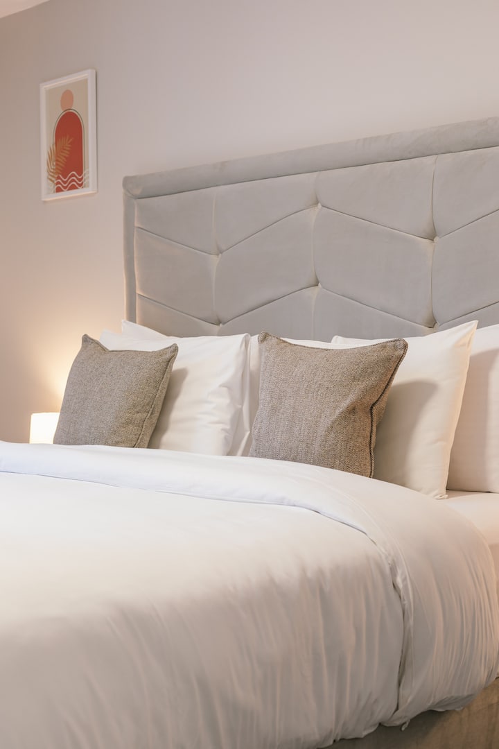 Entra en el dormitorio, un espacio tranquilo y cómodo diseñado para descansar, con una cama lujosa y una ventana que deja entrar luz natural. Es ideal para relajarse después de días completos y disfrutar de noches tranquilas y mañanas lentas durante tu estancia en Belfast.
