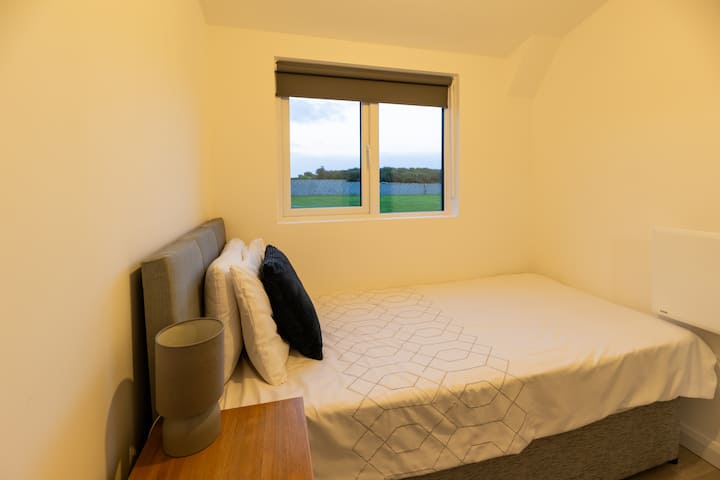 Dormitorio individual: cama individual, unidad de almacenamiento junto a la cama, espejo y espacio para colgar