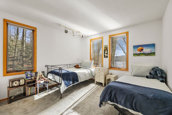 חדר שינה מרווח 1 עם מיטות זוגיות ואזור ישיבה, מלא באור טבעי.