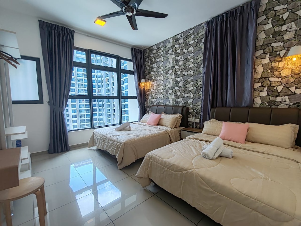 The room contains two spacious beds with neutral bedding and decorative pillows, positioned beside large windows that offer abundant natural light. A textured stone wall adds visual interest, while dark curtains frame the windows. A small chair and a wooden shelf are also included in the space.