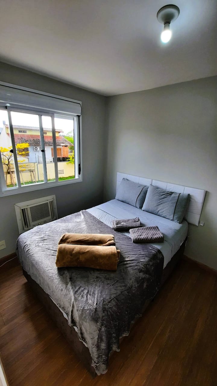 Habitación con cama doble, aire acondicionado, luz natural, cortina opaca, manta y toallas.