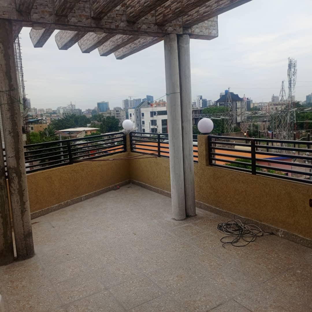 A spacious balcony is shown, featuring a smooth tiled floor and views of the surrounding cityscape. Decorative orbs provide ambient lighting. The balcony is bordered by metal railings, enhancing the open feel of the outdoor space.