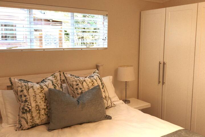 Chumba cha kulala cha kifahari na kilichopambwa vizuri na milango ya Kifaransa hufungua kwenye bustani ya kibinafsi