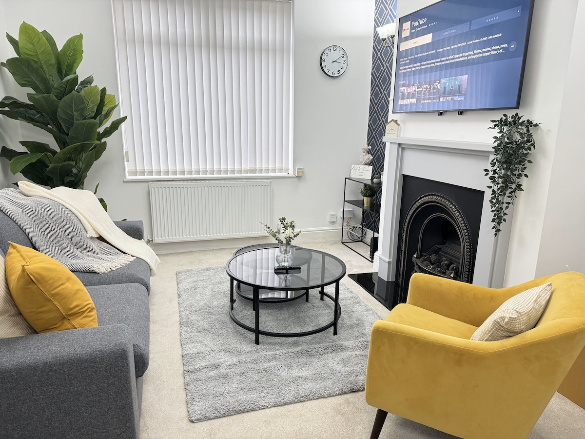 Elegantan, suncem obasjan salon s modernom atmosferom odiše plišanim sivim kaučem, živopisnom žutom stolicom, elegantnim kaminom, pametnim televizorom i staklenim stolićem. Naglašen biljkama, bacačima i blagim osvjetljenjem, savršen je za opuštanje ili emitiranje omiljenih sadržaja.