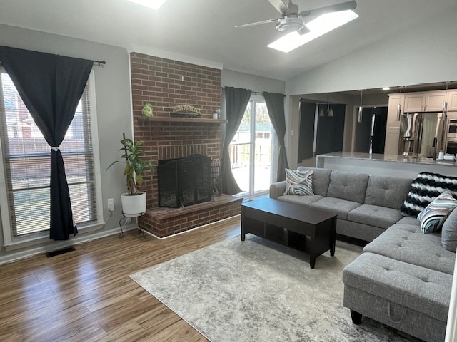 A comfortable living area features a sectional sofa complemented by a coffee table, situated on a light-colored rug. A brick fireplace serves as a focal point, while large windows bring in natural light. Dark curtains frame the windows, contributing to a cozy ambiance.