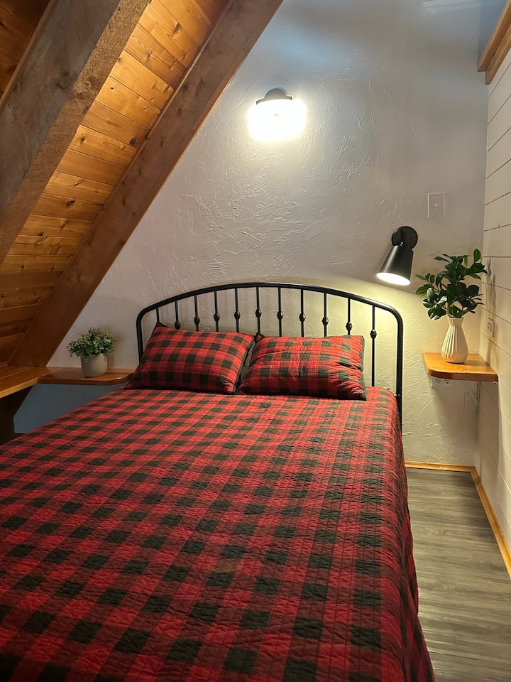 מיטת קווין סייז למעלה עם אחסון מדף.  יש מסך זמין כדי למשוך את החזית כדי לתת פרטיות.