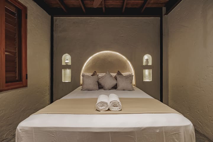 Las habitaciones de Villa La Santísima, con una cama tamaño queen y aire acondicionado, combinan un elegante estilo colonial con el lujo moderno, creando un ambiente sereno y refinado para la relajación.