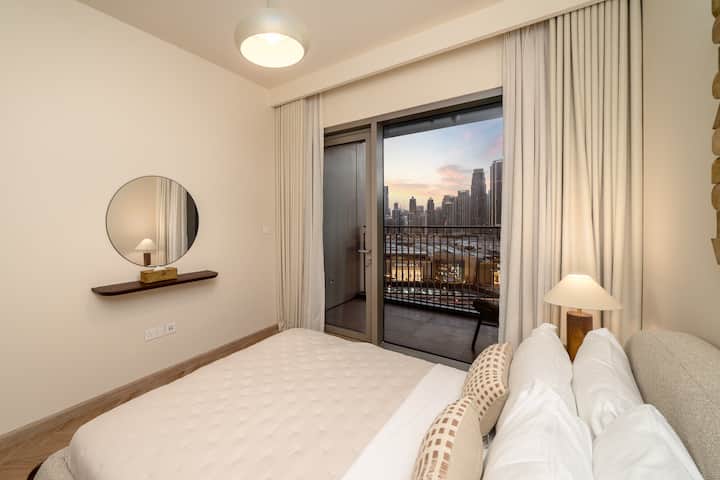 Een stijlvolle slaapkamer met een gezellig bed, modern meubilair en kamerhoge ramen met een adembenemend uitzicht op de stad, zowel overdag als 's nachts.