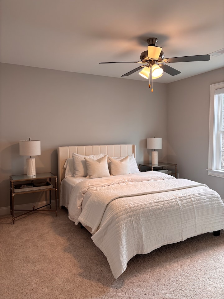 جناح ضيوف في الطابق العلوي يضم سريرًا بحجم كوين وألوانًا محايدة ناعمة ولمسات نهائية أنيقة. يوفر هذا الملاذ الخاص، المجهز بالكامل بتجهيزات حديثة، الراحة والرقي الهادئ للضيوف الزائرين.