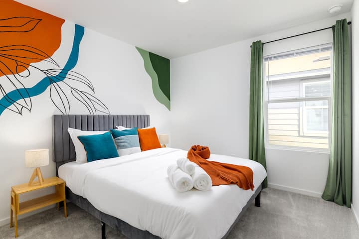 חדר שינה עם מיטת קווין סייז וקיר ציור קיר צבוע ביד. 