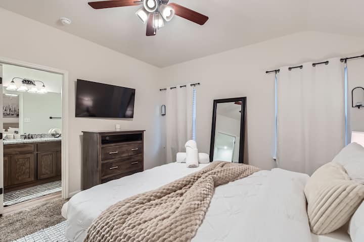 El dormitorio principal cuenta con una cama tamaño queen, un televisor inteligente para el entretenimiento y un baño privado.