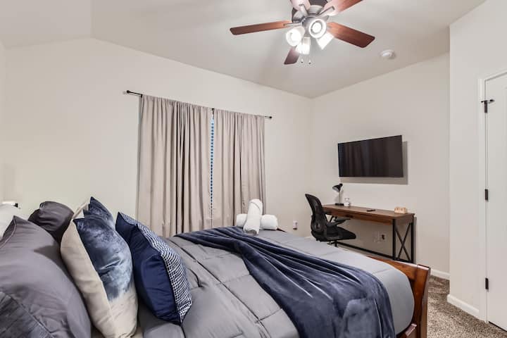 Cama tamaño queen junto con una estación de trabajo y TV inteligente para transmitir en el tercer dormitorio.