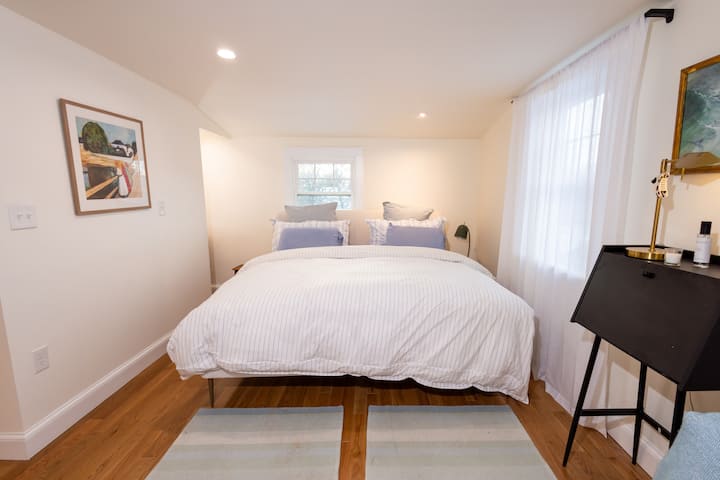 غرفة نوم رئيسية بسرير كينج وخزانة مدمجة وحمام داخلي مع دش زجاجي كثيف القطرات