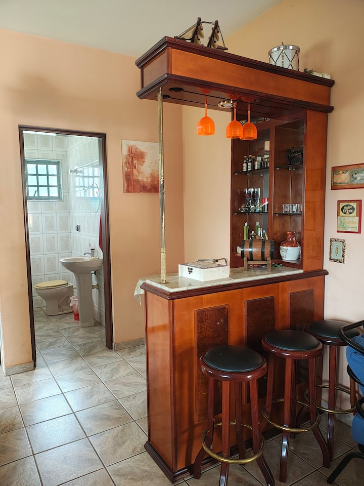 Banja e disponueshme midis dhomës së ndenjjes dhe kuzhinës, për qasje më të lehtë gjatë ngrënies.