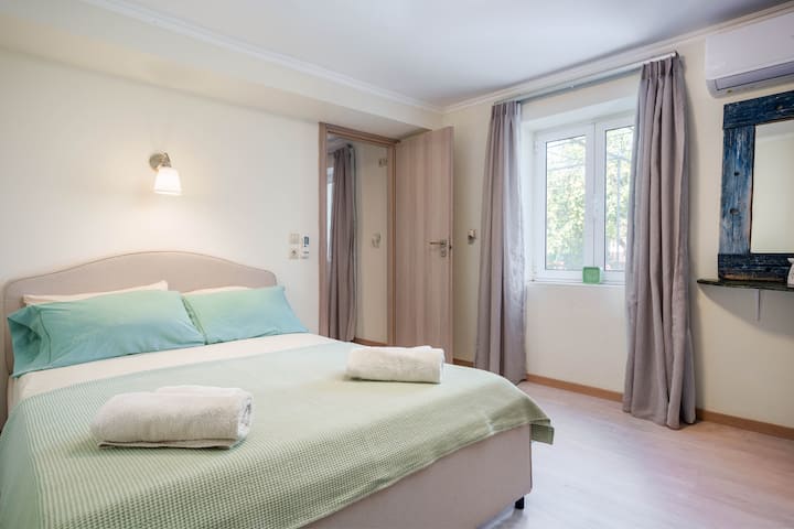 Dormitorio con cama tamaño queen size y ventana al jardín.