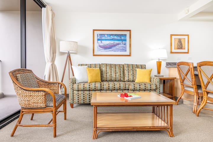 Sala de estar relajante con sofá estampado, sillas de ratán y mesa de centro para disfrutar de noches tranquilas