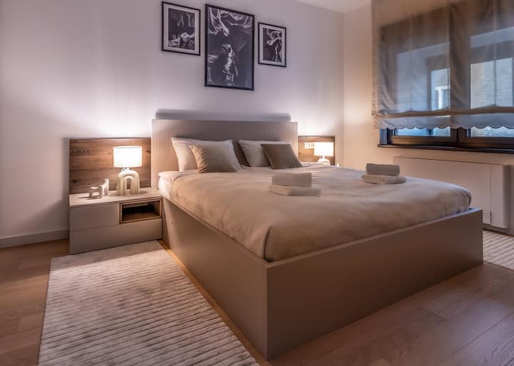 Cozy and quiet bedroom with a comfortable bed, fresh linens, and a warm ambiance featuring motorised blinds 