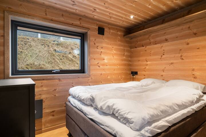 Dormitorio en el primer piso con cama de 150 cm, lámparas de lectura, cargador de teléfono USB / inalámbrico y cortinas donde se puede apagar completamente la luz