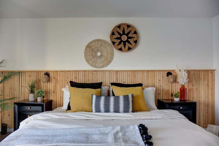 Არაჩვეულებრივი დიდი საწოლი ორი საწოლის გვერდით მაგიდებითა და კედლის საკითხავი განათებით