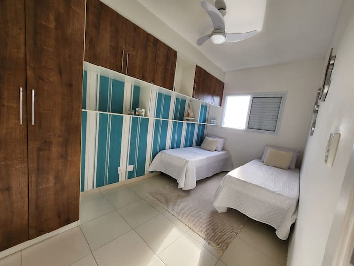 ห้องนอน 1 พร้อมเตียงเดี่ยว 2 หลังฟูกนอนบนพื้นพัดลมเพดานผ้าห่มและหมอนเสริมที่เก็บเสื้อผ้าและเครื่องนอน
