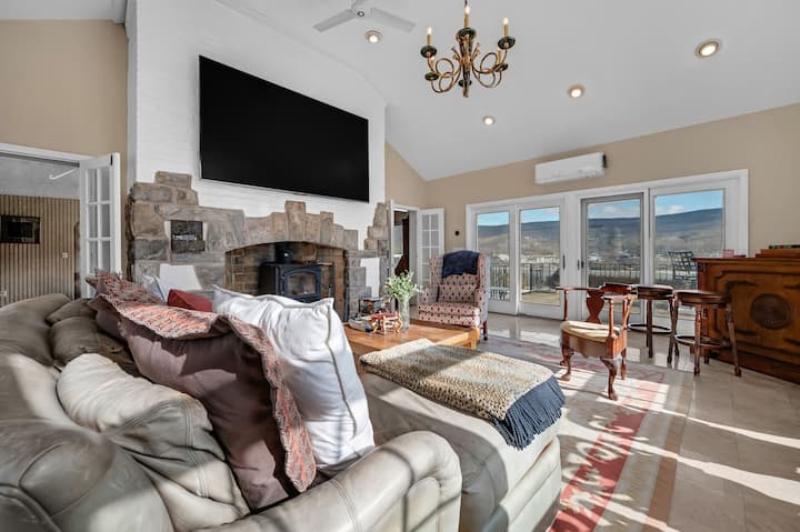 יש טלוויזיה ענקית בגודל 100 אינץ' התלויה מעל האח המקורית ותנור עצים פעיל