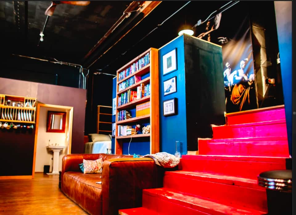 Theater loft living area with a leather sofa, bookshelves, and bright red steps