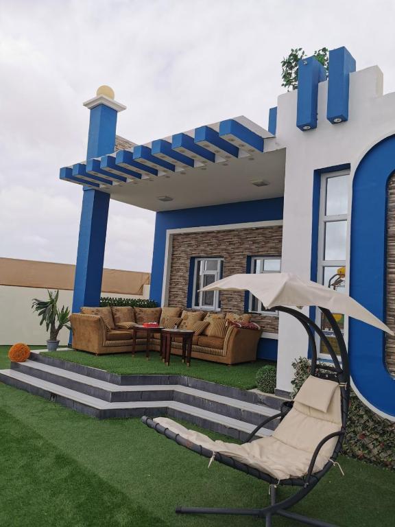 A cozy outdoor seating area is displayed on a terrace, featuring two plush sofas set around a small table. Natural greenery and decorative plants enhance the space, while a beige lounge chair with an umbrella provides additional comfort.