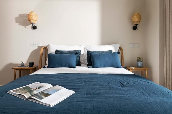 Lit king size de 5 pieds avec couette et oreillers en soie, tables de chevet, éclairage ambiant mural, rail à vêtements, dressing, tabouret, télévision connectée 55", vue sur le port et porte coulissante sur la terrasse.