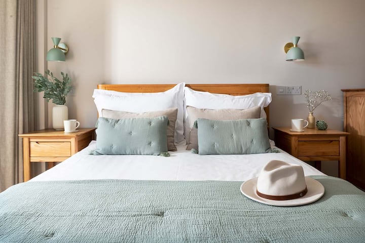 Lit king size de 5 pieds avec couette et oreillers en soie, tables de chevet, appliques murales, commode, armoire, chaise confortable, télévision connectée 55", vue sur le port et porte coulissante sur la terrasse.
