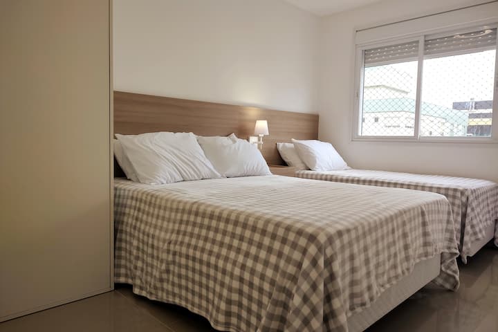 Suite con una cama doble y una cama individual, aire acondicionado, ventana con pantalla protectora y armario para guardar cosas. Sábanas, mantas y almohadas disponibles para usar durante tu estadía.