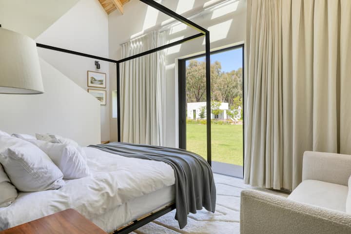 غرفة نوم رئيسية بحمام داخلي مع سرير بحجم كينج ومساحة عمل علوية 