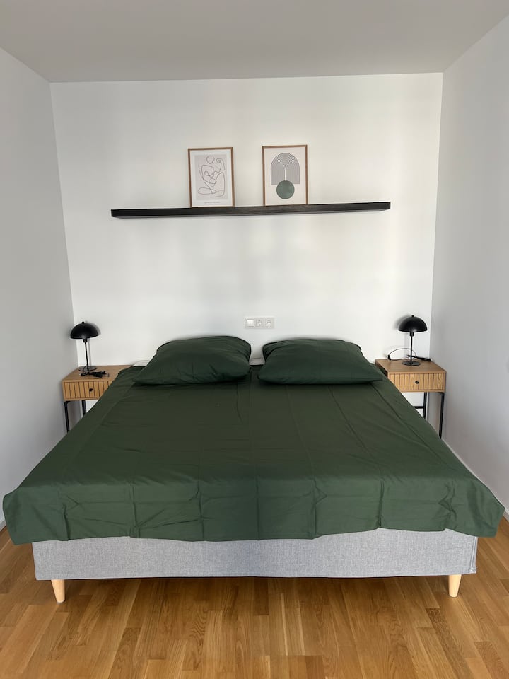 Удобен простор за спиење со висококвалитетен пролетен кревет (двоен кревет) и стилски дизајн. Две ноќни масички со модерни светилки обезбедуваат функционалност и атмосфера – идеални за релаксирачки ноќи во стилски амбиент.