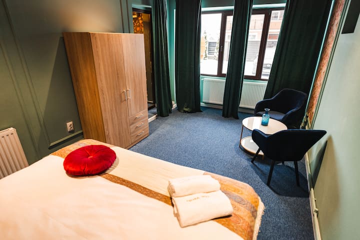 Quarto 5 oferecendo uma cama queen size vestida com lençóis de algodão premium, toalhas macias, armazenamento para suas roupas, área de estar composta por duas cadeiras e uma mesa, aquecimento e persianas escuras