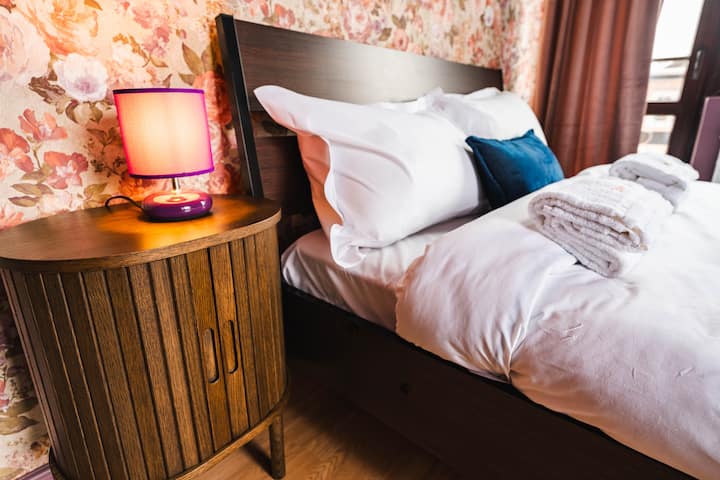 Um vislumbre do quarto um, cama aconchegante com lençóis de algodão premium, lâmpada de iluminação, mesa de cabeceira, sistema de aquecimento e toalhas de qualidade