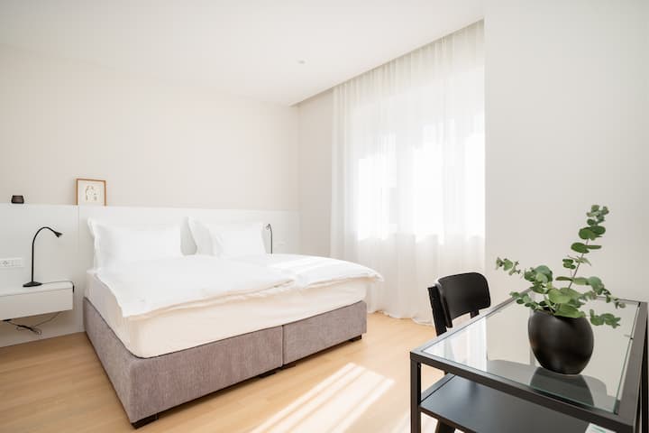 Spálňa je vybavená útulnou manželskou posteľou a vlastnou kúpeľňou pre väčšie pohodlie a pohodlie. Štýlový a dobre osvetlený priestor ponúka relaxačné útočisko s moderným nábytkom a pokojnou atmosférou.