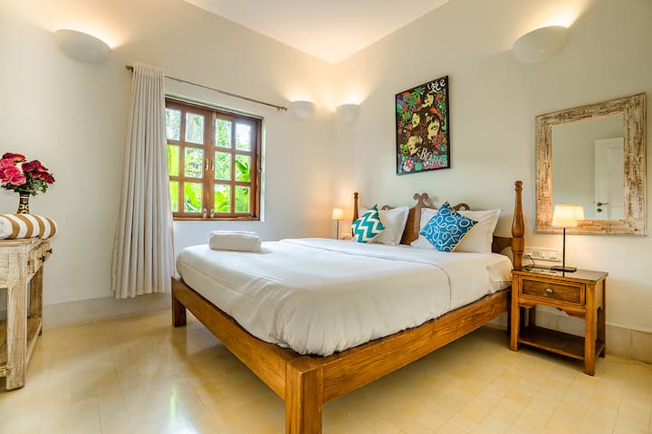 Comfortable and vibrant bedroom in our Goa villa, featuring a cosy bed, stylish décor, and natural light, perfect for a relaxing retreat.