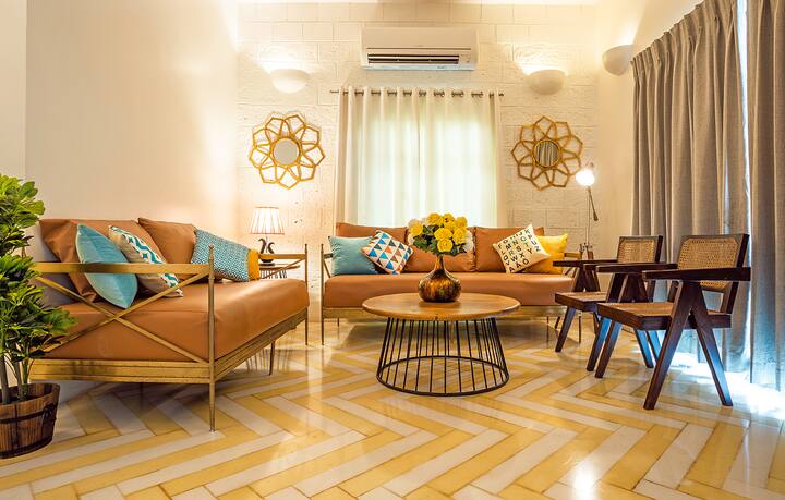 Stylish living area in our Goa villa, featuring comfortable sofas, unique chevron flooring, and charming décor for a truly relaxing and memorable stay.