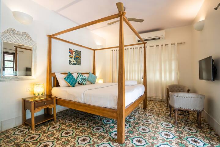 Another charming bedroom in our Goa villa, featuring a comfortable four-poster bed, vibrant floor tiles, and all amenities for a relaxing and stylish stay.