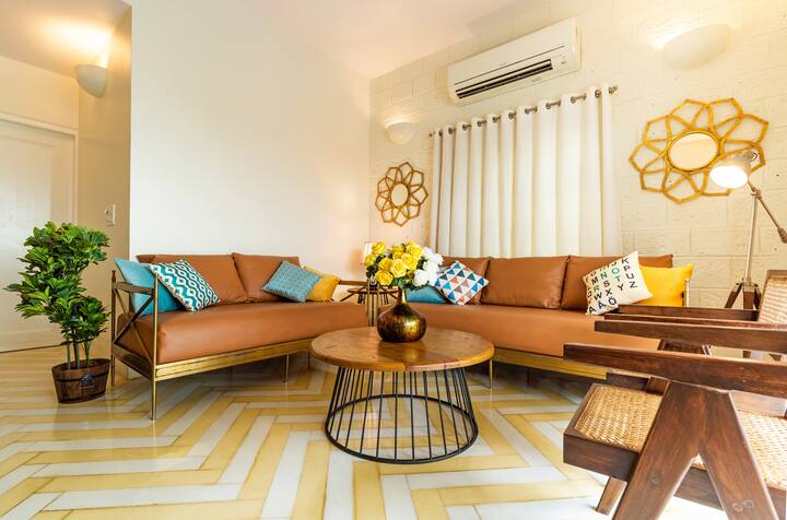Step into comfort at our Goa villa's living room! Relax on stylish sofas with vibrant cushions, admire the unique chevron floor, and enjoy the inviting ambiance.